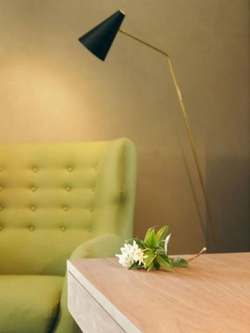 Gemütlicher Sitzbereich mit grüner Polsterung und Stehlampe