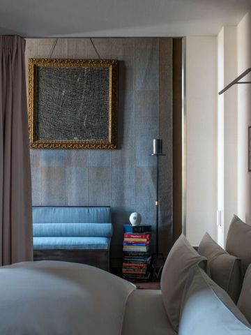 Luxuriöses Schlafzimmer mit hochwertiger Bettwäsche und Kunst an der Wand.