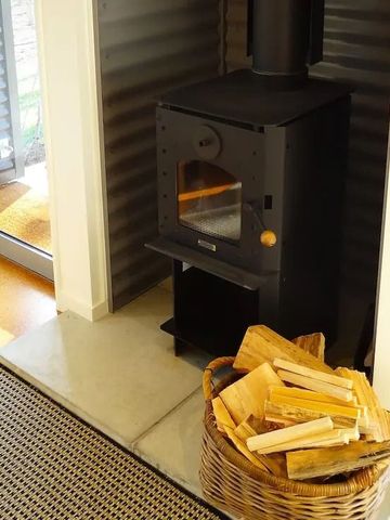 Holzofen mit Brennholz in einem eleganten Raum mit großem Fenster.