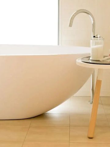 Freistehende Badewanne neben einem stilvollen Beistelltisch