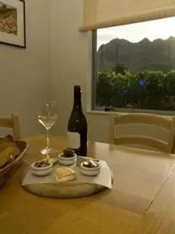 Gemütlicher Essbereich mit Wein und Snacks vor einem Fenster mit Bergblick.