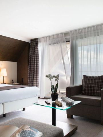 Helles Hotelzimmer mit großem Fenster, gemütlicher Einrichtung und stilvollem Interieur