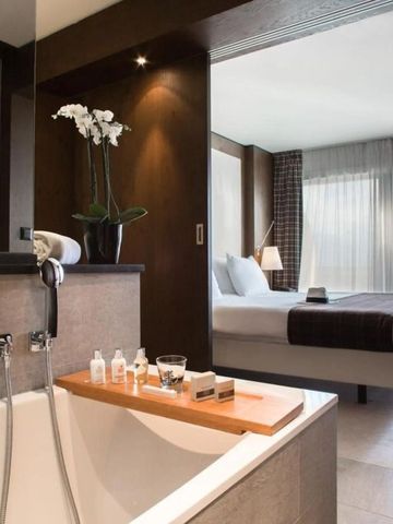 Modern gestaltetes Hotelzimmer mit freistehender Badewanne und Blick auf das Bett