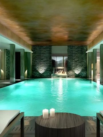 Luxuriös beleuchtetes Hallenbad mit Kamin und eleganten Liegen