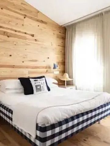 Holzverkleidetes Schlafzimmer mit stilvollem Doppelbett und großem Fenster.
