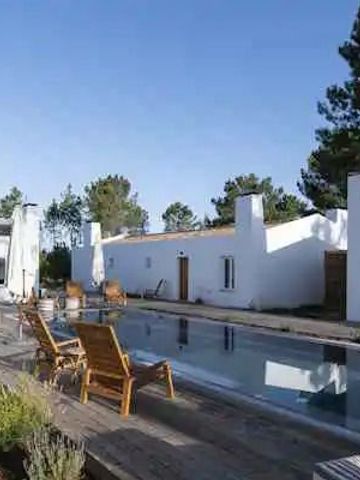 Außenpool mit Liegestühlen umgeben von weißen Gebäuden und Bäumen