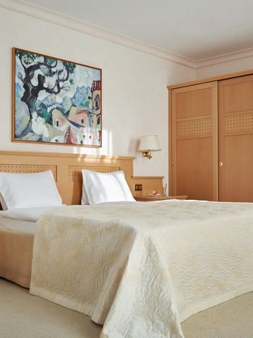 Elegantes Doppelzimmer mit Doppelbett und modernem Kunstwerk an der Wand