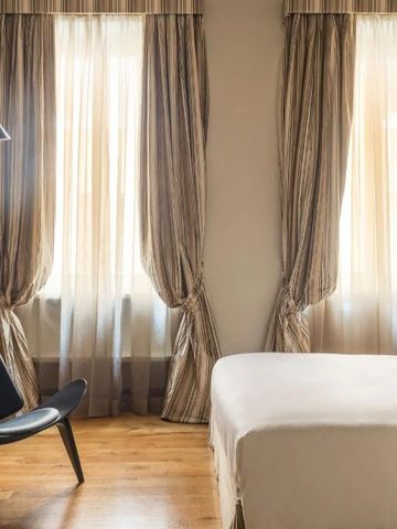 Luxuriöses Schlafzimmer mit eleganten Vorhängen und Holzboden