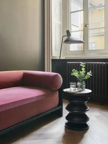 Hotelzimmer mit Sofa und Beistelltisch vor Fenster.