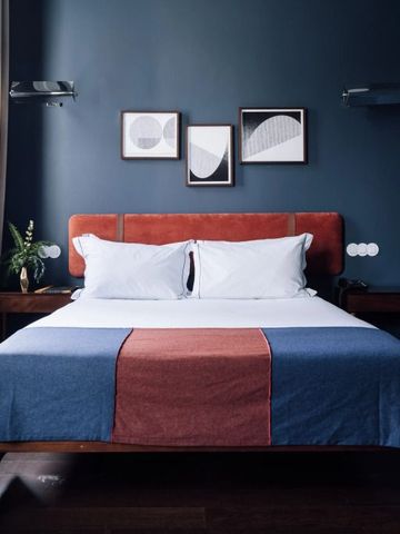 Doppelbett in modernem Zimmer mit dunkelblauer Wand und Kunstwerken im The Vintage Lisbon Hotel