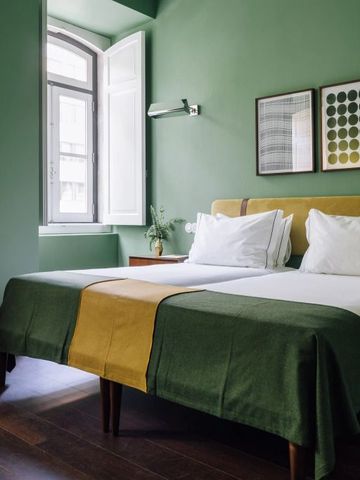 Gemütliches Zimmer mit zwei Betten und grünen Wänden im The Vintage Lisbon Hotel