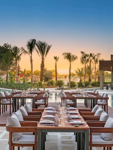 Gedeckte Tische am Pool mit Palmenhintergrund bei Sonnenuntergang