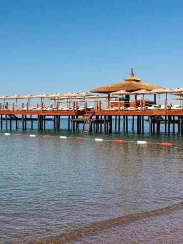 Holzsteg mit Sonnenschirmen und Liegen über dem klaren Meer