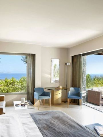 Lichtdurchflutetes Zimmer mit Sitzbereich und Blick auf Terrasse sowie Meer.