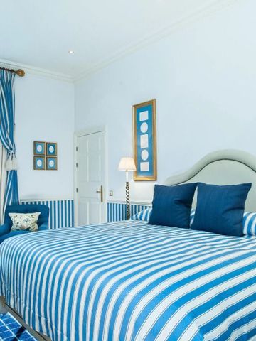 Helles Zimmer im Hotel d'Angleterre mit blau-weißen Streifen auf Bett und Möbeln