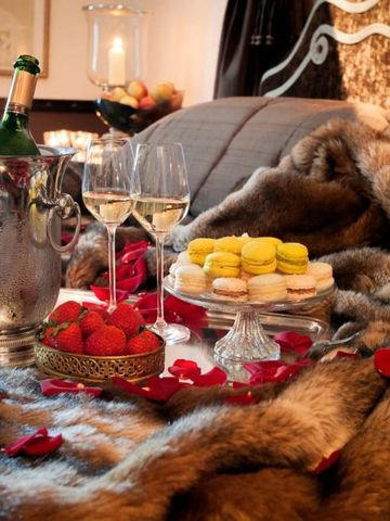 Gemütliches Ambiente mit Rosenblättern und Champagner auf dem Bett