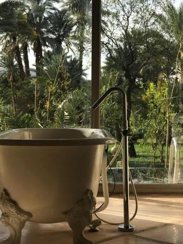 Freistehende Badewanne mit Aussicht auf Garten und Palmen im Dar Hnini Hotel