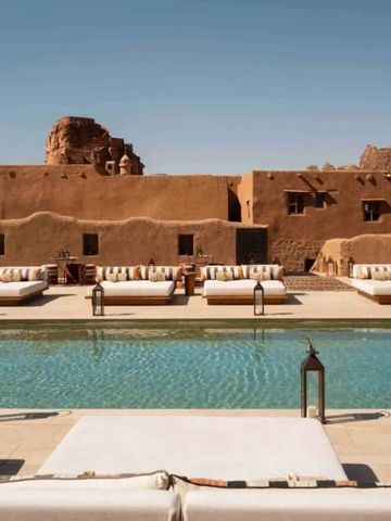 Luxuriöser Poolbereich mit bequemen Liegen vor traditioneller Architektur