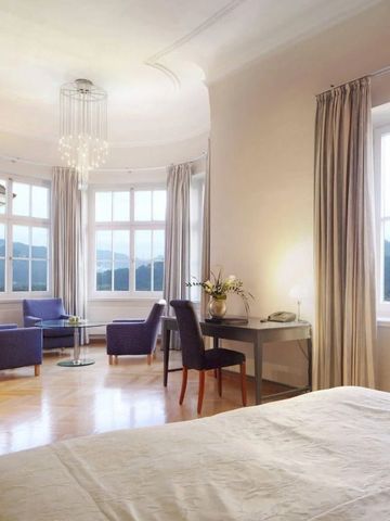 Elegantes Zimmer mit Parkettboden, gemütlicher Sitzgelegenheit und Panoramablick auf die Berge