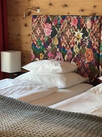 Hotelzimmer mit farbenfrohem, floralem Kopfteil und dicken Kissen