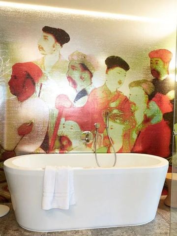 Design-Badezimmer mit freistehender Wanne und kunstvoller Wandgestaltung