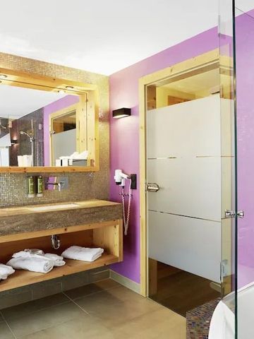Modernes Badezimmer mit violetten Wänden und Glasdusche im Boutique-Hotel