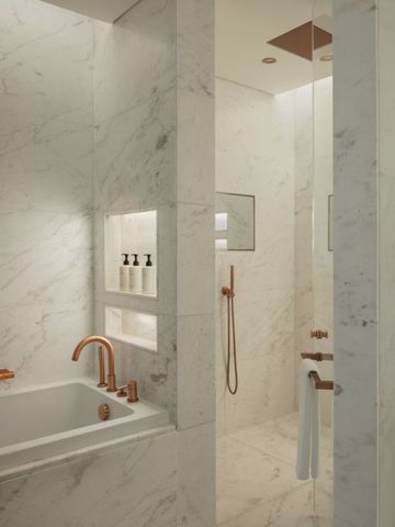 Luxuriöses Badezimmer mit Marmordesign und Kupferarmaturen.