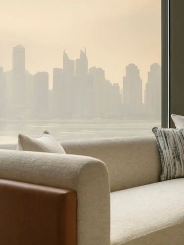 Ausblick auf Dubais Skyline durch ein elegantes Wohnzimmersetting mit cremefarbenem Sofa.