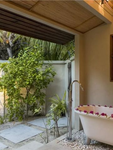 Freistehende Badewanne in einem offenen Badezimmer mit Gartenblick.