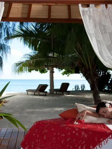 Frau entspannt auf einer Liege am Strand mit Meerblick.