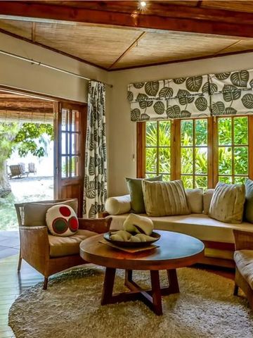 Gemütliches Wohnzimmer mit großen Fenstern und tropischem Ausblick.