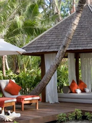 Luxuriöse Gartenlaube mit Liegen und Palmen