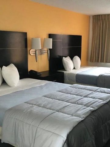 Zwei Doppelbetten in einem Hotelzimmer mit warmen Farbtönen