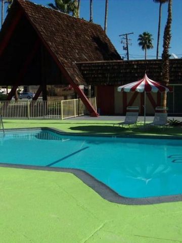 Pool mit Liegestühlen und Sonnenschirmen, umgeben von Palmen