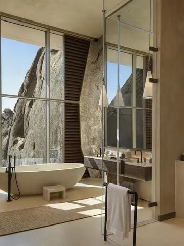 Luxuriöses Badezimmer mit freistehender Badewanne und großer Fensterfront zu Felsen.