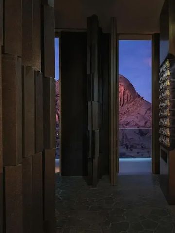 Gang mit Blick auf beleuchtete Felsen in der Abenddämmerung.