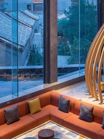 Helles Lounge-Bereich mit Sitzgelegenheiten und großen Fenstern.