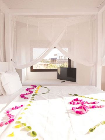 Romantisch dekoriertes Bett mit Blumen und einem großen Fenster