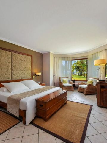 Helles Schlafzimmer mit großem Doppelbett und Sitzbereich am Fenster