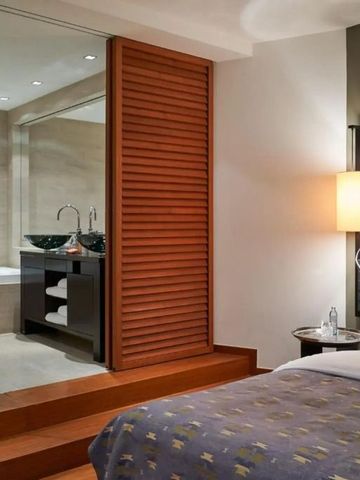 Luxuriöses Zimmer mit Blick auf das Badezimmer. Holzlamellentür als Abgrenzung