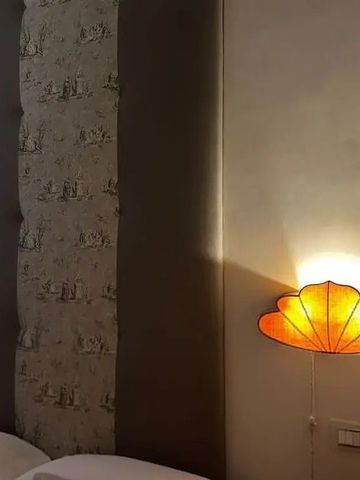 Detail eines stilvollen Hotelzimmers mit dekorativen Lampen und geflochtenem Kopfteil.