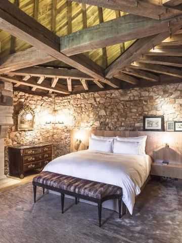 Luxuriöses Schlafzimmer mit Sichtbalken und Steinwänden