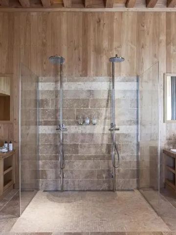 Luxuriöses Badezimmer mit Doppelwaschbecken und modernen Duschen aus Holz und Naturstein