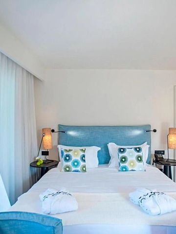 Modern eingerichtetes Hotelzimmer mit blauem Kopfteil und stilvollen Lampen