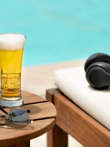 Poolblick mit Getränken, Sonnenbrille und Kopfhörer auf einer Liege.