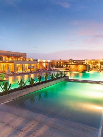 Beleuchteter Pool bei Sonnenuntergang mit Blick auf Hotelgebäude und Pflanzen