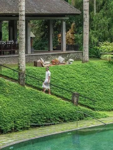 Grüner Garten mit Blick auf einen glitzernden Pool und traditioneller Pavillon.