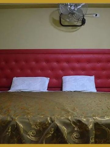 Komfortables Bett mit rotem gepolstertem Kopfteil in einem Hotelzimmer