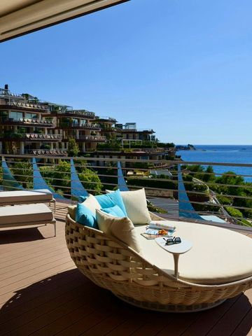 Luxuriöse Terrasse mit Rattan-Liege und Meerblick bei klarem Himmel