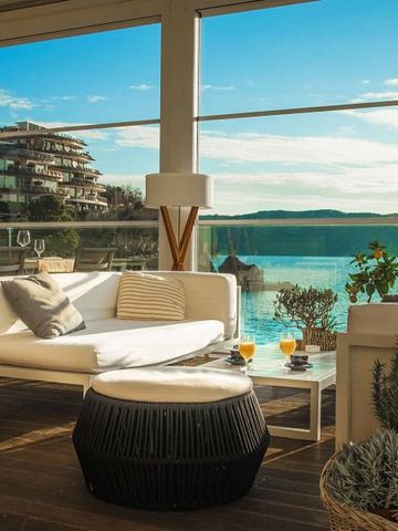 Terrasse mit Meerblick und gemütlichen Sitzgelegenheiten im Sonnenlicht.